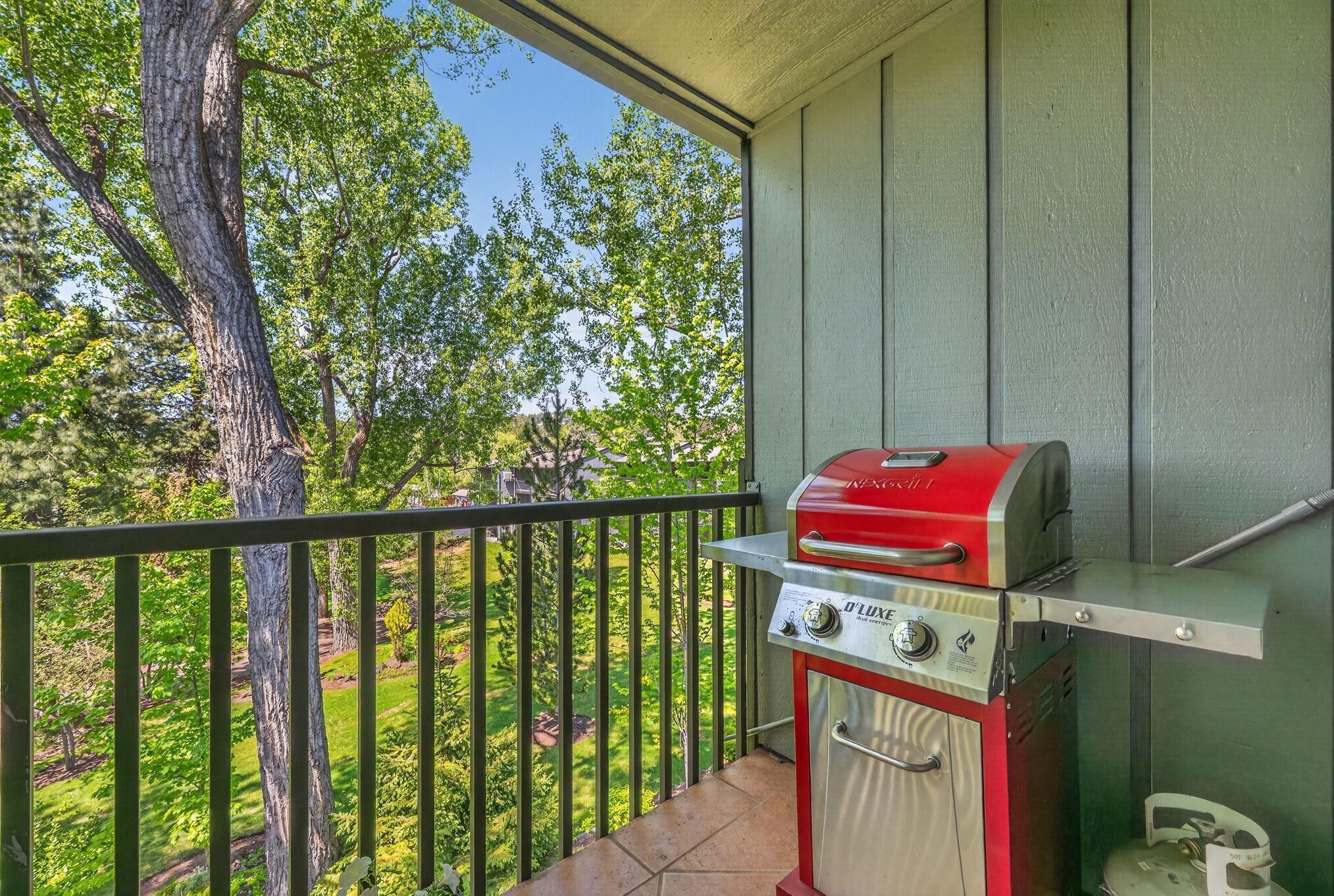 Un balcon avec un barbecue et une bouteille de gaz.