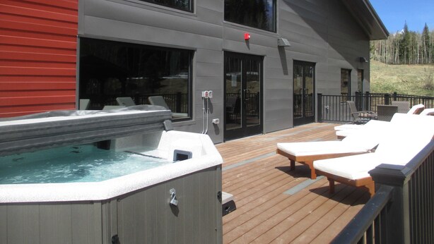 Ein modernes Gebäude mit Whirlpool und Liegestühlen auf einer Holzterrasse.