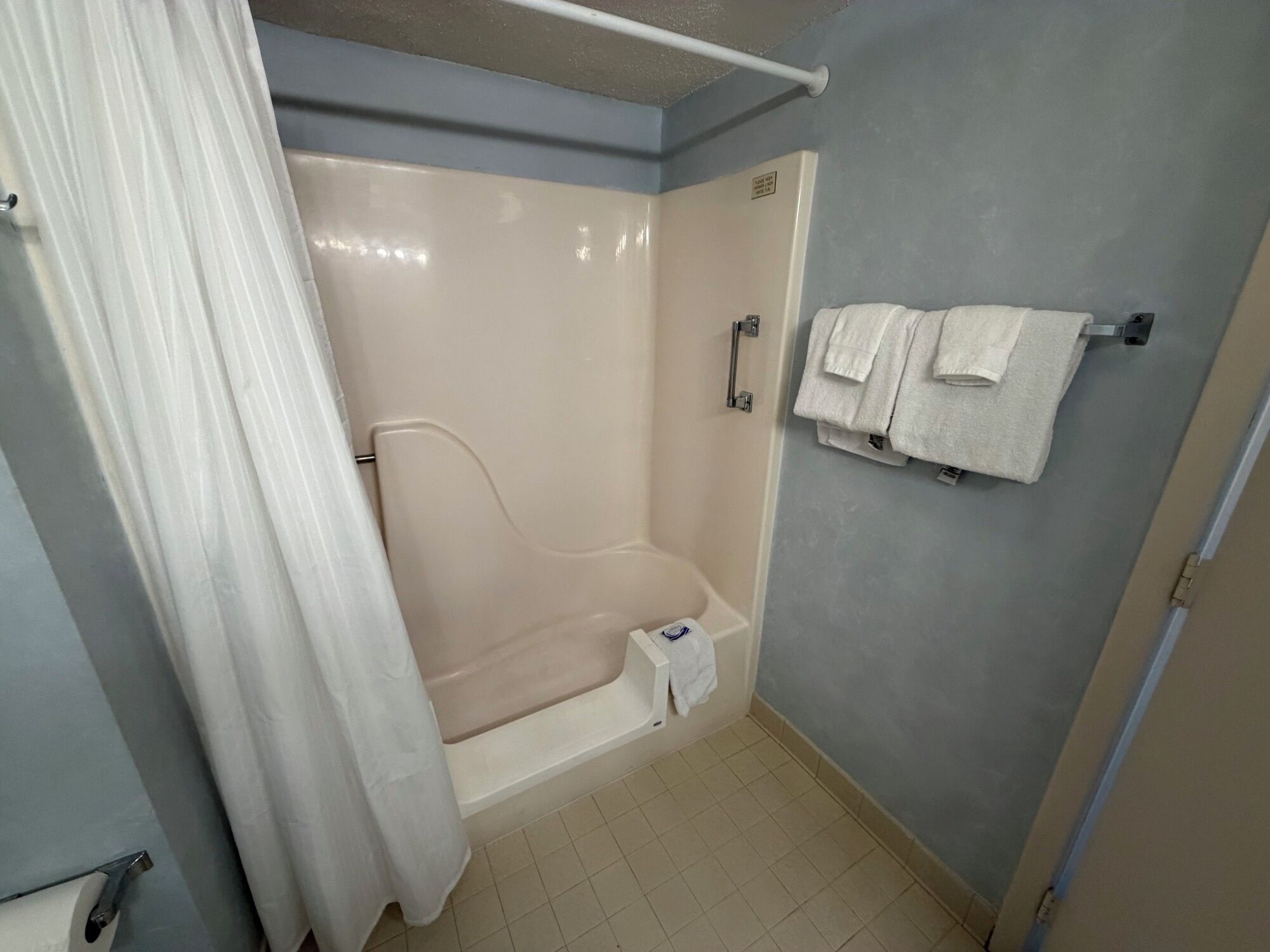 A bathroom with a shower, a towel rack, and a toilet.