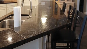 A kitchen with a granite countertop, stainless steel sink, and a hanging light fixture. - Upscale Beach & Golf Getaway At Bayside Resort (Selbyville)