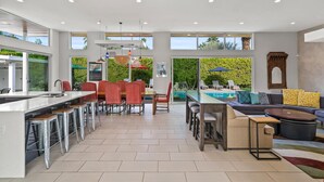 Una cocina amplia con comedor, una piscina y una sala de estar con sofá y mesa de centro.