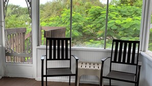 A covered porch with two wooden chairs and a small table.