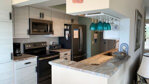 Una cocina moderna con electrodomésticos de acero inoxidable, encimera de mármol y microondas integrado.