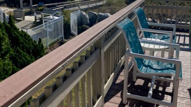 Una terraza de madera con barandilla, con vistas a la playa y el océano.