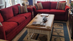 A living room with two red sofas, a wooden coffee table, and a globe lamp.
