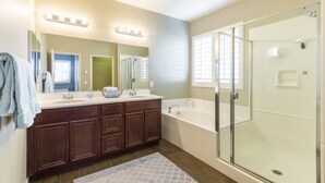 Une salle de bain moderne dotée d’une douche à l’italienne, d’un grand miroir et d’un meuble-lavabo avec un évier et plusieurs tiroirs.