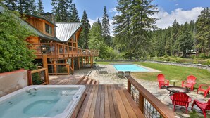 A wooden deck with a hot tub, outdoor seating, and a pool area surrounded by trees. - Heaven Can Wait Lodge ~ Riverfront Estate on 12 Private Acres ~ Expansive Views (Leavenworth)