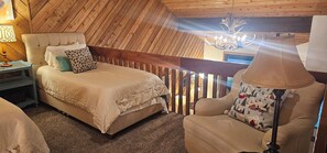 Een slaapkamer met een bed, nachtkastje, stoel en een kroonluchter.