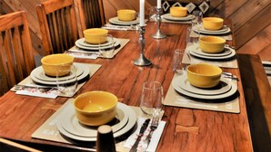 Une table à manger dressée avec des bols, des assiettes et des couverts jaunes, le tout devant un mur en bois et surmonté d’une enseigne indiquant « MAMMOTH ».