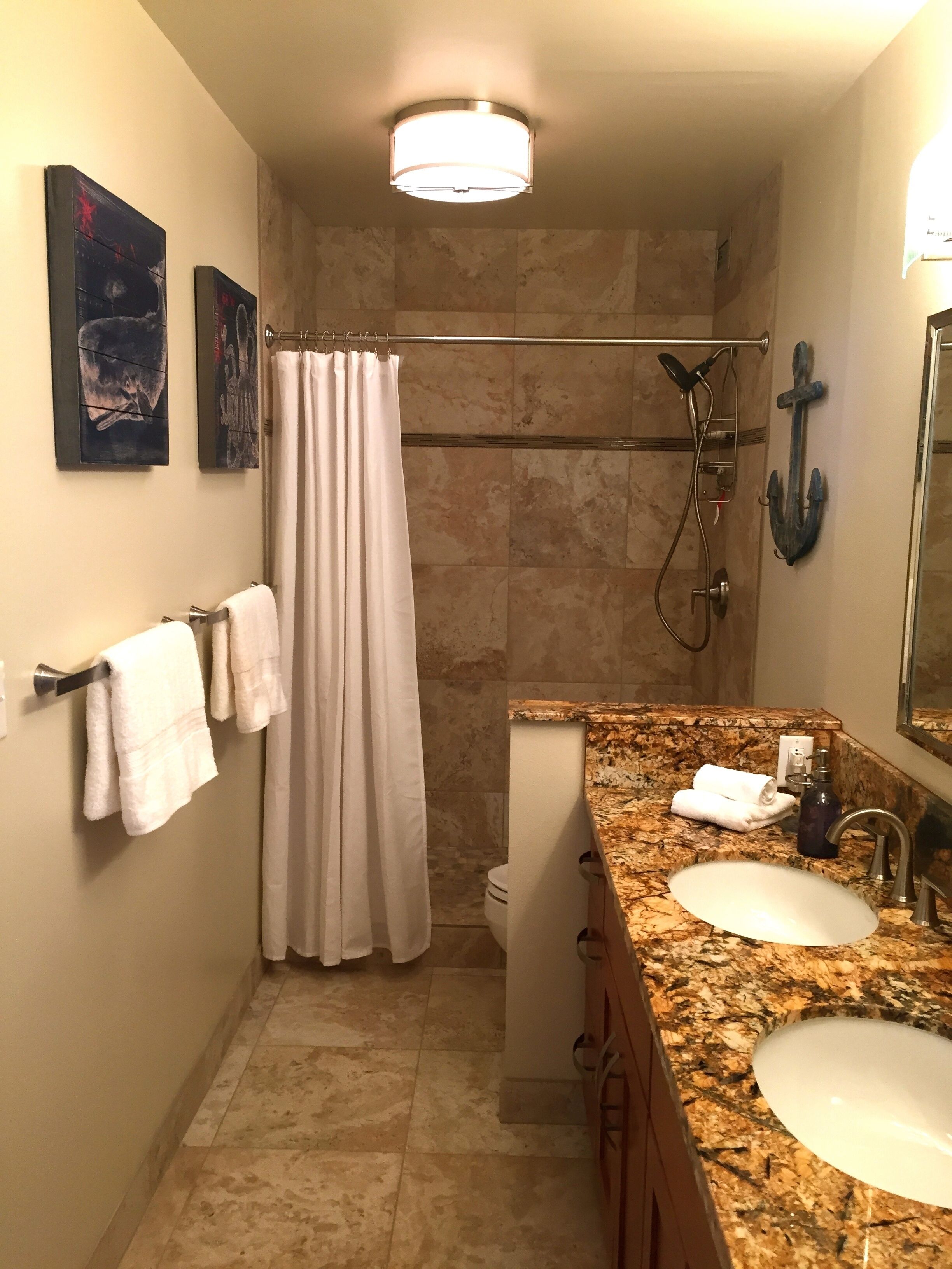 A bathroom with two sinks, a shower, and a towel rack with towels.