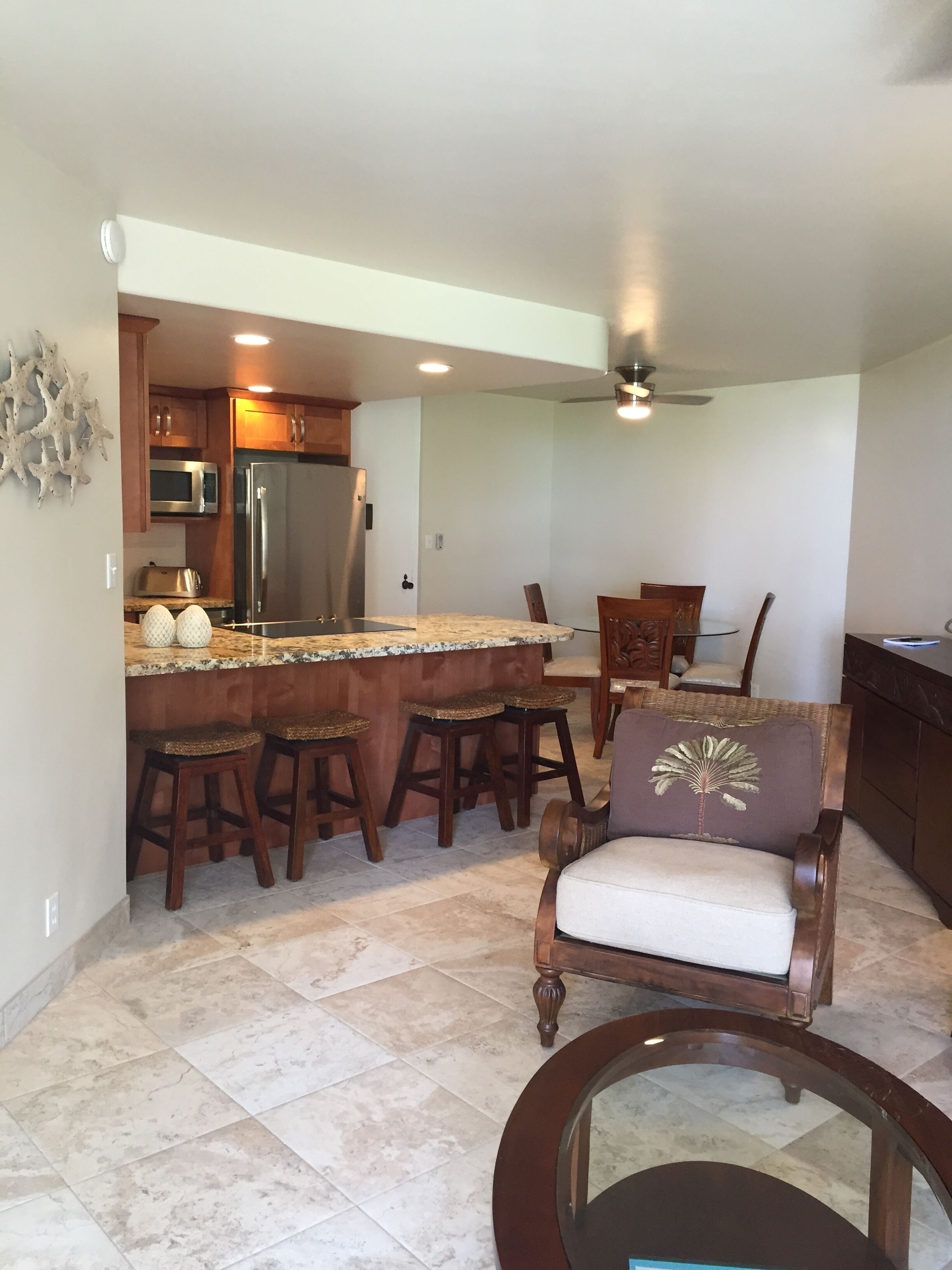 A kitchen with a central island, bar stools, a microwave, and a refrigerator.