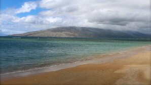 A beach with clear water, a sandy shore, and a mountain in the background. - Beautiful, Ocean Front Condo With An Ocean View In Sunny Kihei, Maui! (Kihei)