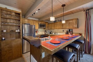 Una cocina con armarios de madera, un refrigerador de acero inoxidable, un microondas y una isla grande con asientos.