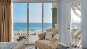 A balcony with a view of the beach, a patterned armchair, and a door with blinds. - Oceanfront 2BR Condo at Long Beach Resort, Panama City Beach, sleeps 6. (Panama City Beach)