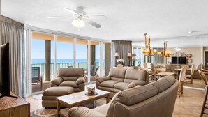 A spacious living room with a large sofa, armchairs, and a coffee table. There is a balcony with a view of the ocean. - Oceanfront 2BR Condo at Long Beach Resort, Panama City Beach, sleeps 6. (Panama City Beach)