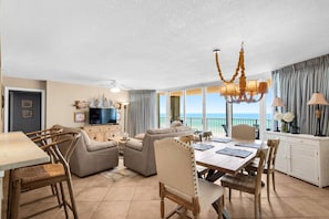 A spacious living area with a dining table, sofas, and a television.