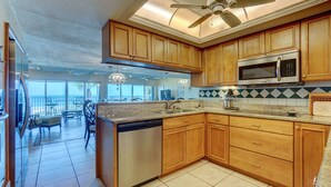 A kitchen with wooden cabinets, a dishwasher, and a microwave. - BEAUTIFUL CONDO WITH PERFECT VIEW OF BEACH AND GULF WITH NEW HEATED POOL (Indian Rocks Beach)