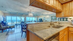 A spacious kitchen with wooden cabinets, granite countertops, and a dishwasher. - BEAUTIFUL CONDO WITH PERFECT VIEW OF BEACH AND GULF WITH NEW HEATED POOL (Indian Rocks Beach)