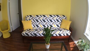 A living room with a sofa, a glass coffee table, and a potted plant. - DOWNTOWN COZY APARTMENT (St Augustine)