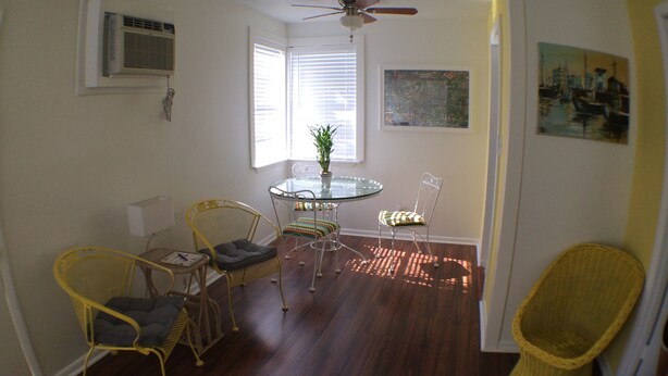 A dining area with a round glass table, two chairs, and a ceiling fan. - DOWNTOWN COZY APARTMENT (St Augustine)