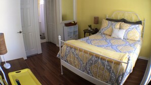A bedroom with a bed, a ceiling fan, a bedside table with a lamp, and a small table with a plant. - DOWNTOWN COZY APARTMENT (St Augustine)