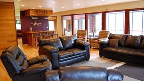 A spacious living room with leather sofas and a bar area.