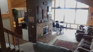 A spacious living area with a fireplace, a dining table, and a sofa. - Sun, Sand, Snow, Year Round Recreation, With Private Beach (Roscommon)