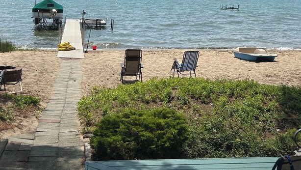 A wooden deck leading to a sandy beach with a dock and a small boat. - Sun, Sand, Snow, Year Round Recreation, With Private Beach (Roscommon)