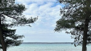 A wooden deck with a round table and chairs overlooking a beach and the sea. - Sun, Sand, Snow, Year Round Recreation, With Private Beach (Roscommon)