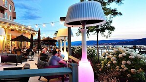 An outdoor seating area with tables and chairs, string lights, and umbrellas. - 5 ⭐️ Unit 437 - Sol Terra Stays - Bright 2 bdrm with Pool & Courtyard Views (Kelowna)
