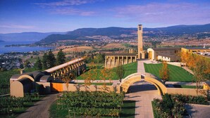A campus with a prominent clock tower, green lawns, and a view of the surrounding landscape. - 5 ⭐️ Unit 437 - Sol Terra Stays - Bright 2 bdrm with Pool & Courtyard Views (Kelowna)