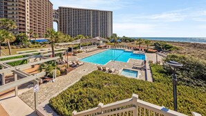 Ein Resort mit großem Pool, Liegestühlen und Meerblick.