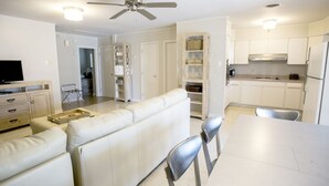 Een moderne keuken met witte kasten, een eettafel en een plafondventilator.