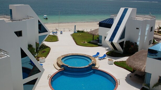 A modern resort with a pool, lounge chairs, and a beach view.