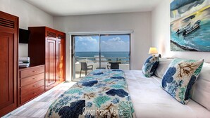 A bedroom with a bed, a large window, and a view of the ocean.
