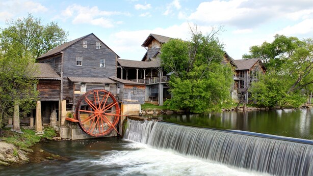Un bâtiment historique doté d’une grande roue à eau et d’une cascade.