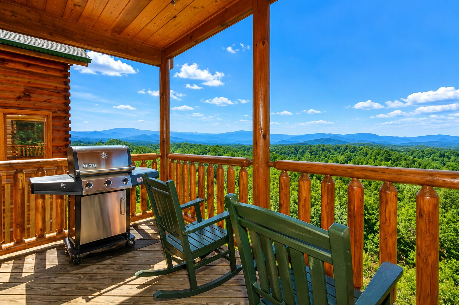 Eine Holzterrasse mit Grill und Stühlen mit Blick auf eine bewaldete Landschaft.