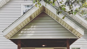 A house with a red door, a porch, and two large flower pots. - Modern Designer Beach House 1 mile to the beach! Pet-friendly & bright (Sawyer)