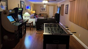 A living room with a foosball table, a gaming console, a sofa, a TV, and a ceiling fan. - 8 Bedrooms, 12 beds, pool, hot tub,putting green, pool table, ping pong, bbq (Phoenix)