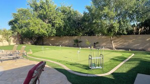 A well-maintained lawn with a putting green, stone patio furniture, and a metal swing set. - 8 Bedrooms, 12 beds, pool, hot tub,putting green, pool table, ping pong, bbq (Phoenix)