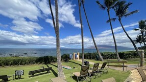 A poolside area with lounge chairs and a view of the ocean.