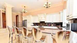 Une cuisine moderne avec des meubles blancs, des appareils en acier inoxydable et un coin bar équipé de tabourets.
