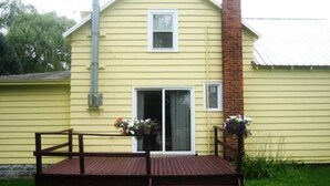 A yellow house with a wooden deck, a brick chimney, and a window with a white frame. - Unique FarmStay Experience in The Catskills! (Durham)