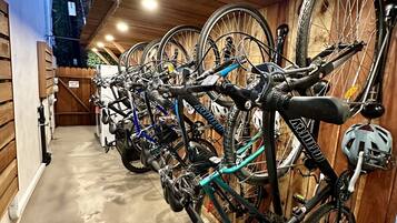 Une rangée de vélos est garée à l’intérieur, devant un mur et un plafond en bois.