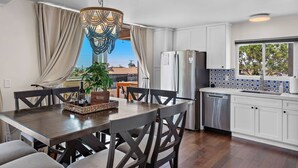 Una cocina moderna con armarios blancos, un refrigerador de acero inoxidable y un salpicadero de azulejos azules y blancos.