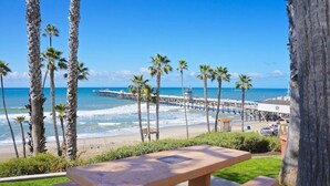 Vista de una playa con palmeras, un muelle y una mesa de picnic.