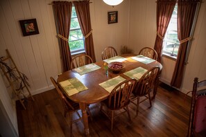 Un comedor con una mesa de madera, seis sillas y un jarrón de flores.