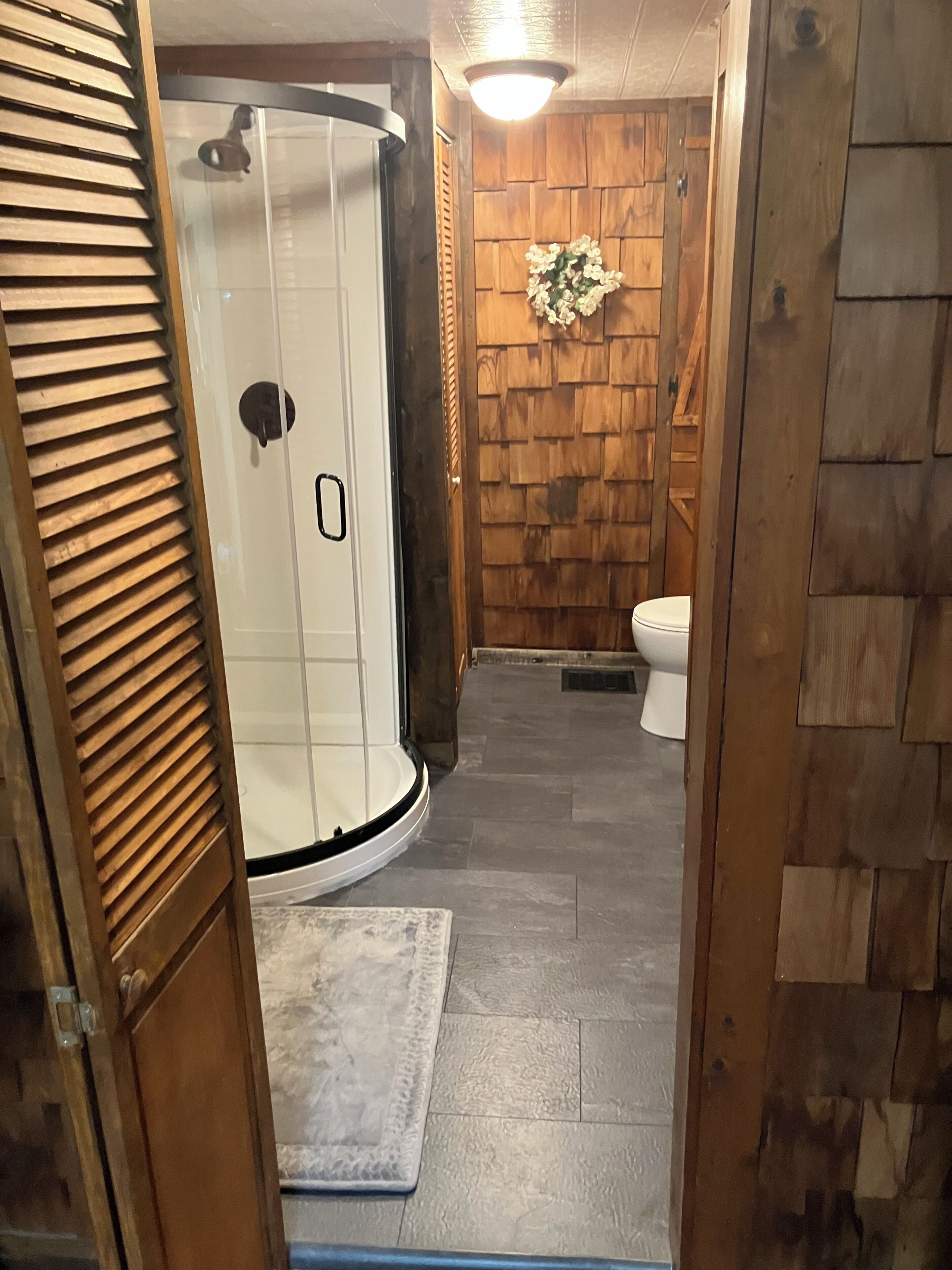 Een badkamer met douche, toilet en houten wandbekleding.