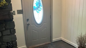 A gray door with a frosted glass window, a stone wall, and a wooden floor.