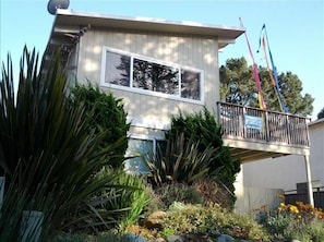 A two-story building with a balcony, surrounded by various plants and flowers. - Westside 3 BR + loft  Overlooks Natural Bridges Beach. Great for Families! (Santa Cruz)